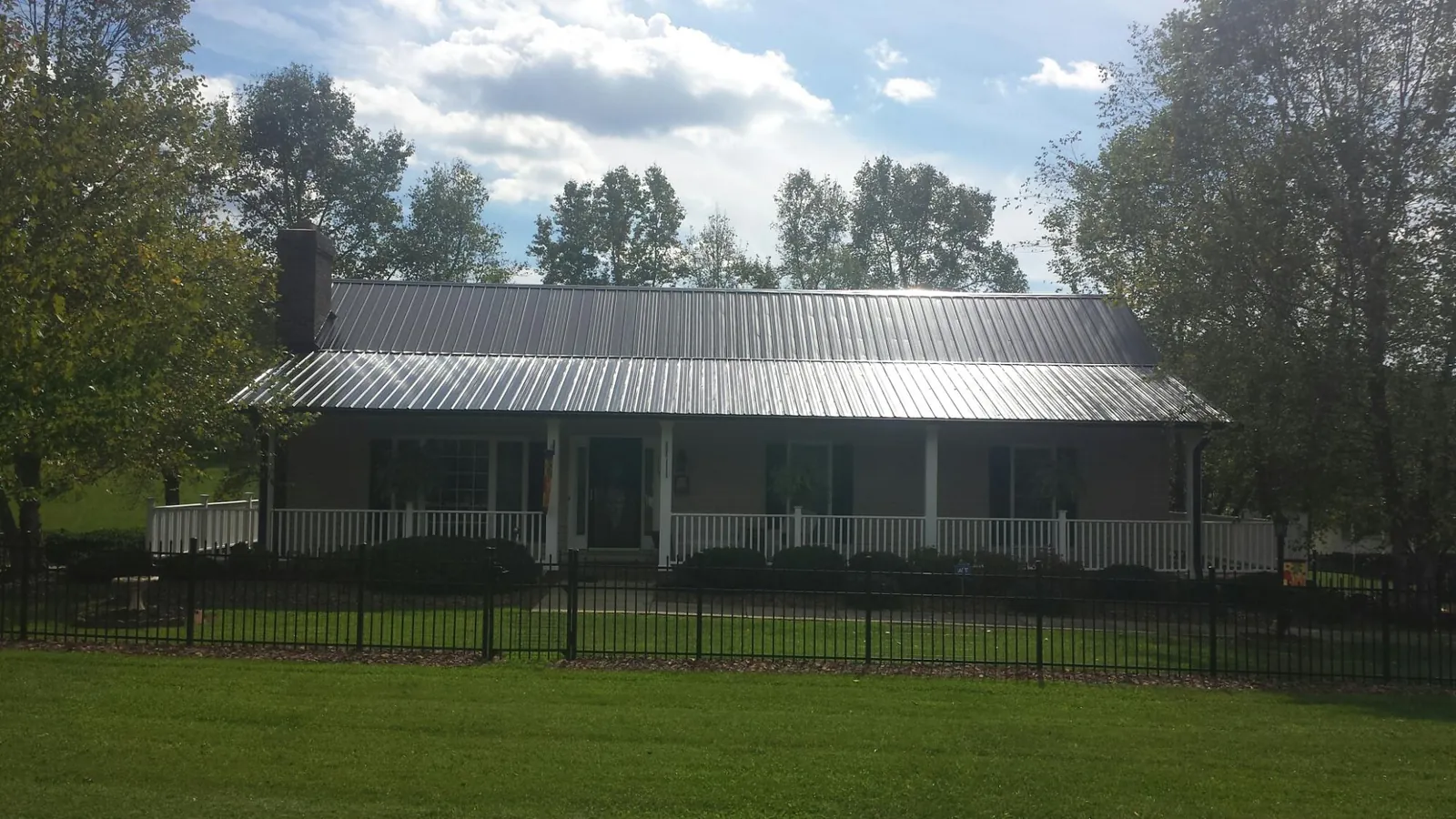 Gray metal roof on a brick ranch with a full width front porch — Gutter Guard Installation work by our crew in Inkster